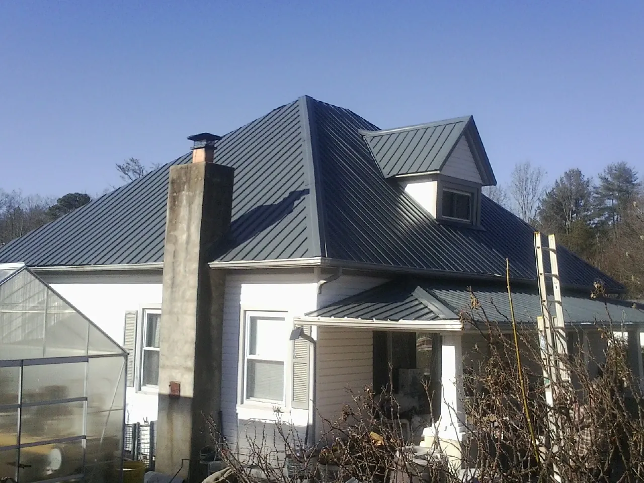 Dark blue standing seam metal roof on a white farmhouse with dormer — Slate & Tile Roof Repair by Roofing Brothers in Fox Island