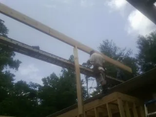 Carpenter setting a ridge beam over a new addition frame — Ice Dam Removal by Roofing Brothers in Fox Island