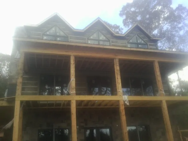 Dormers and porch framing on a large log home under construction — Roof Coating work by our crew in Fox Island