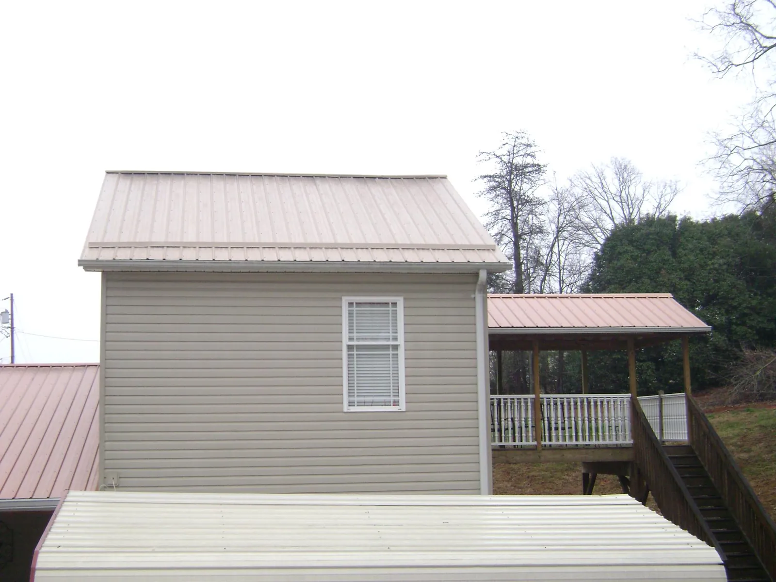 Tan metal roofs on a two story addition and attached porch, from a Roof Replacement job in Fox Island