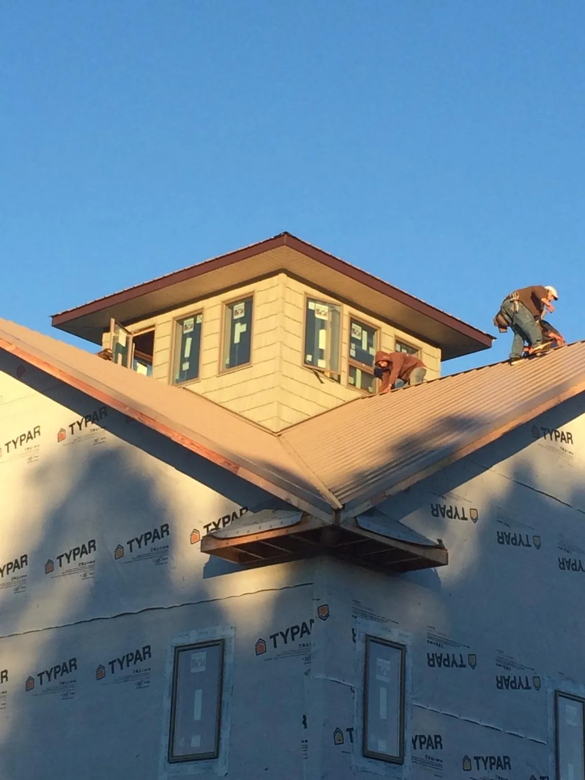 Roofers working around a rooftop cupola on a new metal roof at sunset — Roof Waterproofing in Fox Island by Roofing Brothers